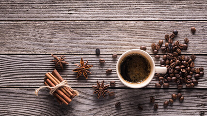 top view glass cup with espresso, coffee beans, star anise and cinnamon sticks on a gray wooden...