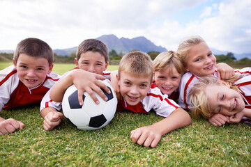 Children, soccer ball and relax on green grass or field for outdoor match, game. or team sports. Group of kids, friends or football players smile lying together for competition on stadium in nature