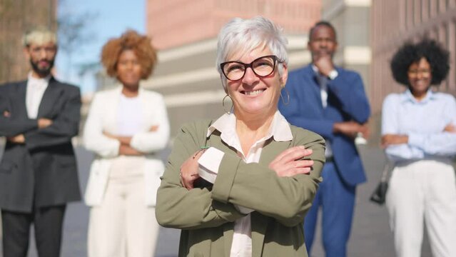 Smiling mature businesswoman standing in front of a business team
