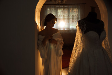A beautiful brunette bride with a tiara in her hair is getting ready for the wedding in a beautiful...