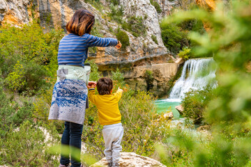 Woman and son walking on the path next to the waterfalls of the Vero River walkways in Alquezar....
