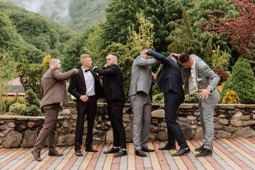 Cheerful, young, energetic witnesses of the groom next to the groom. Friends congratulate the groom. Groom and his funny friends having fun on the wedding day of the newlyweds. - obrazy, fototapety, plakaty
