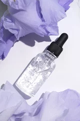 Meubelstickers Serum with floral extracts for skincare. Nature cosmetics in glass bottle with pipette and iris flowers on marble background. Face and body care spa concept. © Ionica