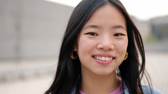 Asian young woman smiling at camera in the street