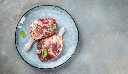 Fresh duck leg meat set with herbs on a light background top view. copy space