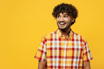 Young surprised shocked smiling happy Indian man he wearing shirt casual clothes look aside on workspace area copy space isolated on plain yellow color background studio portrait. Lifestyle concept.