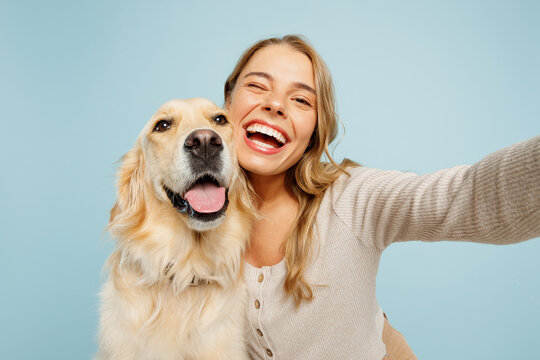 Close up young owner woman with her best friend retriever dog wear casual clothes do selfie shot on mobile cell phone wink isolated on plain pastel light blue background. Take care about pet concept.