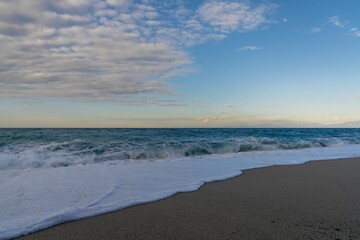 Fototapeta na wymiar view of the golden sand Rotonda Beach in Tropea with turquoise water and waves crashing onshore