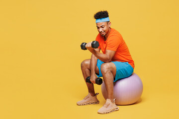 Full body sad young fitness trainer sporty man sportsman wearing orange t-shirt sit on fit ball...