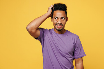 Young dissatisfied confused man of African American ethnicity he wears purple t-shirt casual...