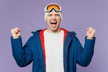 Skier man in warm blue windbreaker jacket ski goggles mask do winner gesture celebrate clench fist spend extreme weekend winter season in mountains isolated on plain purple background. Hobby concept © ViDi Studio