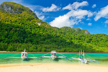PALAWAN, PHILIPPINES - DECEMBER 21, 2023: Local traditional outrigger tour boat with tropical...