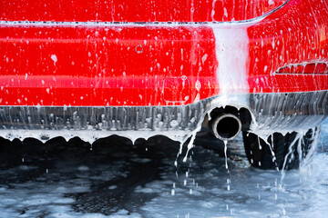 Exhaust of a red car being washed.