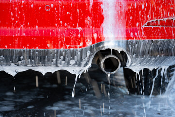 Exhaust of a red car being washed.
