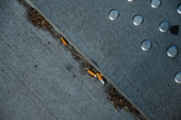 Cigarette buds littered on a pavement.