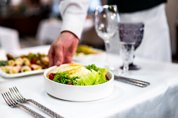 Men's waiter hands hold a Caesar salad 