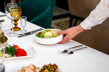 Men's waiter hands hold a Caesar salad 