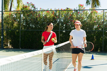 Happy young women friends on the tennis court