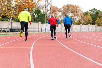 A trio of senior runners in mid-action on a red track, vividly showcasing their commitment to...