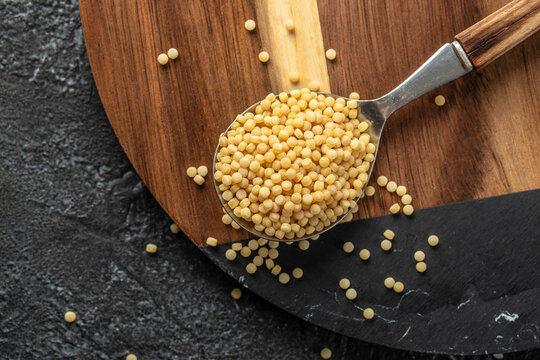 Raw pasta fregola sarda ricette on a dark background. top view. copy space for text