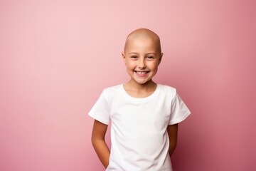 young little girl with cancer without hair smiling on pink background. Cancer day concept