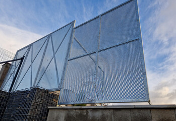 construction of a brick fence to prevent thieves from climbing into the garden. perforated metal sheet fence in the shape of squares with bracing against the wind, design, modern, windbreaker