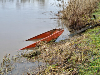 a sunken fishing boat hangs on a chain. after the rains, there is more water in the river and...
