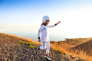 Astronaut futuristic kid girl with white full length uniform and helmet wearing silver shoes...