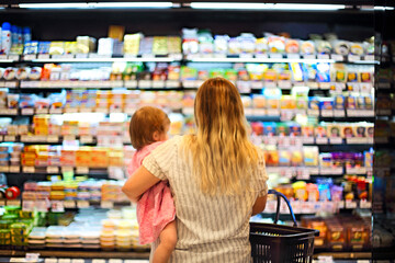 Cheerful mother and baby spending time in shopping in supermarket
