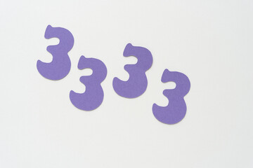 machine-cut purple paper number three on blank paper