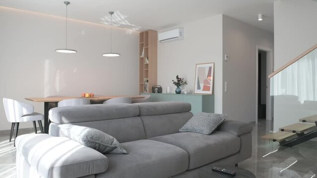 A smooth flight through a bright Scandinavian style room with grey furniture and a glass staircase