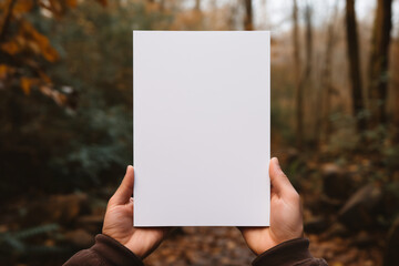 Hands presenting a blank white board outdoors with autumn leaves background