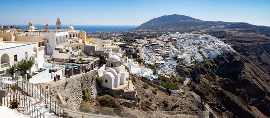 Ein Panorama mit Stadtansicht von Fira, der Hauptstadt von Santorin in Griechenland. - obrazy, fototapety, plakaty