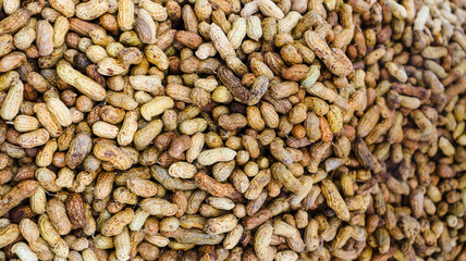 Close-up view of background of a pile of ripe peanuts. Peanut shell texture background on a pile of peanuts.