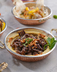 Hummus plate with meat, garnished with mint, toasted almonds and olive oil