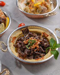 Hummus plate with meat, garnished with mint, toasted almonds and olive oil
