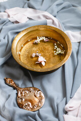 Fancy hand mirror and bowl of water among leaves and flowers prepared for skin care procedure