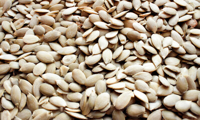 Background with raw hulled pumpkin seeds close-up