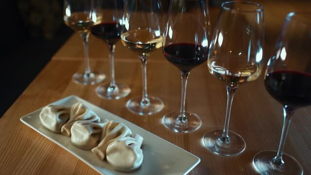 Georgian khinkali dumplings with red and white wine in glasses on wooden table