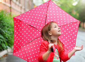 Little girl with polka dots umbrella under the rain
