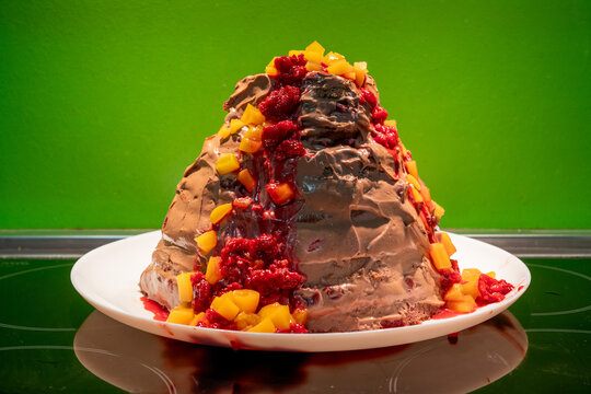 Homemade chocolate and fruit cake in a shape of a volcano in front of a green background, shallow depth of field