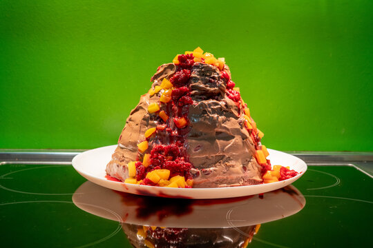 Homemade chocolate and fruit cake in a shape of a volcano in front of a green background, shallow depth of field