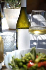 bottiglia di vino bianco al tavolo di un ristorante all'aperto - obrazy, fototapety, plakaty