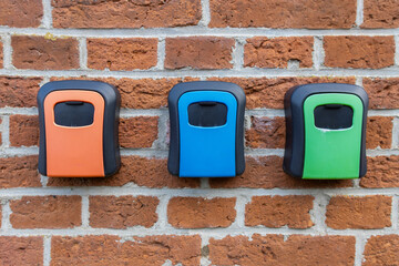 Multiple colored key lock boxes, key safe, on brick wall background, contactless check in short...