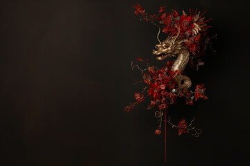 Small statue of golden Chinese dragon decorated with red flowers for Chinese New Year on black background