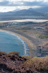 Elevated views from the volcanic peak Montana Roja towards the natural beach Playa de la Tejita and nearby resort surrounded by farms and plantations and rugged land in Tenerife, Canary Islands, Spain