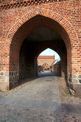 Fototapeta na wymiar medieval gate and walls made of stone and brick in the city of Neubrandenburg