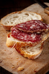 Slices of italian salami on slices of rustic bread. Front view.