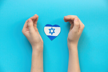 child's hands and a drawn Israeli flag in the shape of a heart on a blue background. concept Israel...