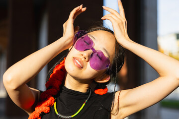 ASIAN GIRL POSING WITH RELAXED COLORED GLASSES